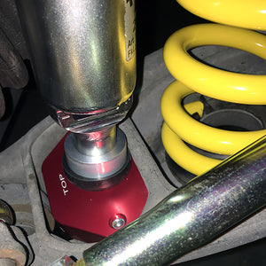 Installation picture of red BMW E90, E92, E82 lower rear shock mounts with poly bushings (street). Made in USA by AKG Motorsport.