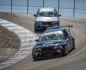 A black BMW E46 M3 race car at Laguna Seca with AKG performance parts installed.