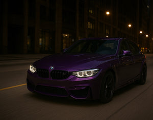 A purple BMW F80 M3 driving through the city at night with AKG performance parts.