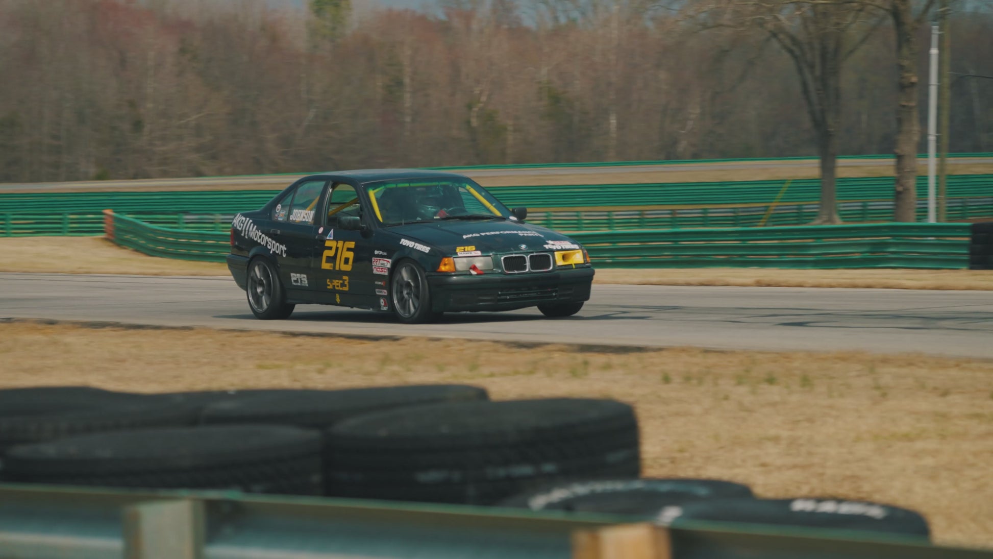 An E36 spec3 race car racing on track at VIR with AKG performance parts.